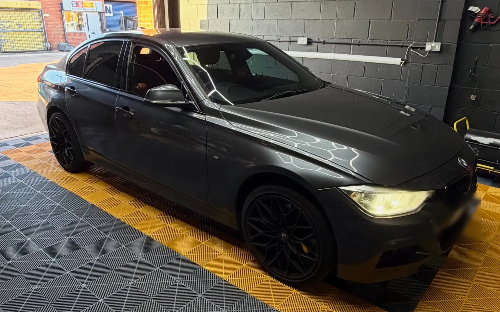 A black BMW F30 3 Series in the CODEMYBM workshop bay